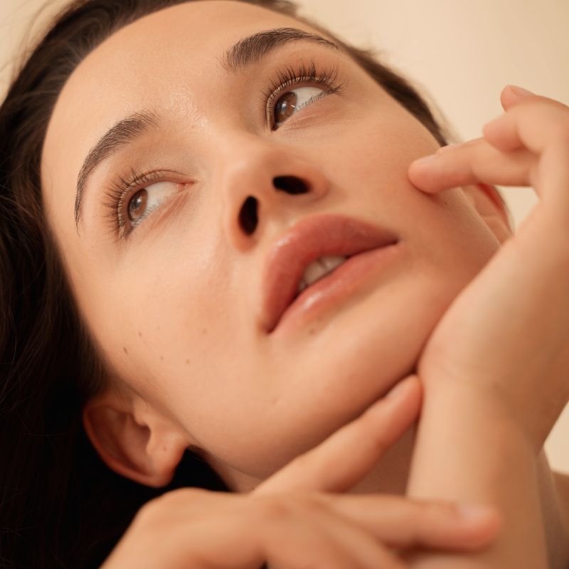 A woman touching her face promoting DiamondGlow treatment in Salt Lake City and Provo, UT